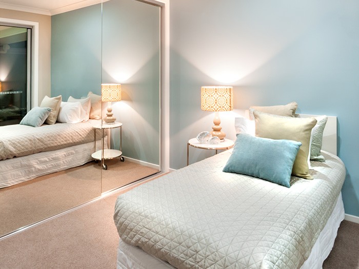 Small bedroom featuring mirrored closet doors.